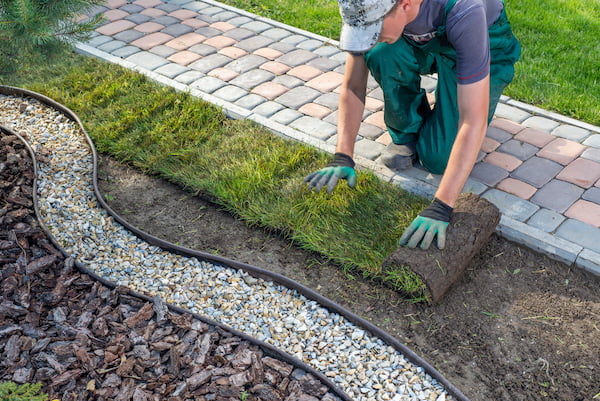 Landscaper rolling turf showing how to dispose of landscape waste